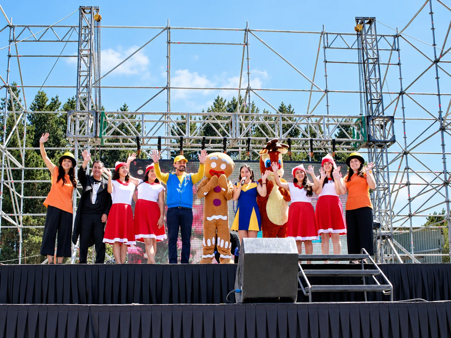 Elenco sobre un escenario al aire libre.